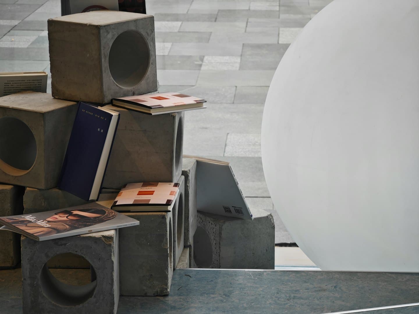 Bloques de hormigón gris y libros con una esfera blanca.