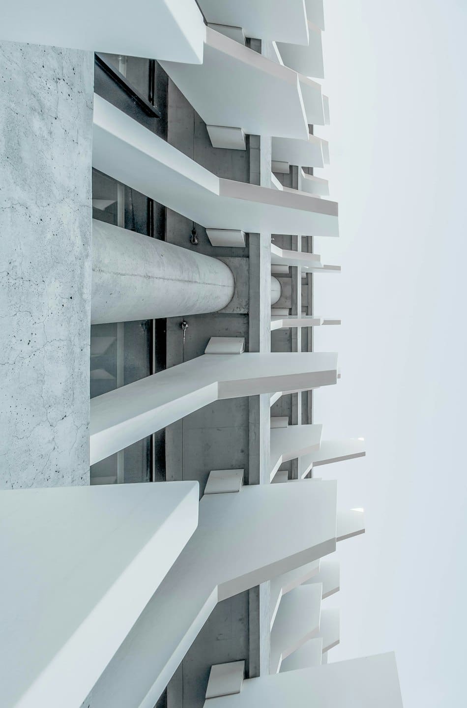 Edificio moderno con losas blancas repetidas y muros de hormigón.