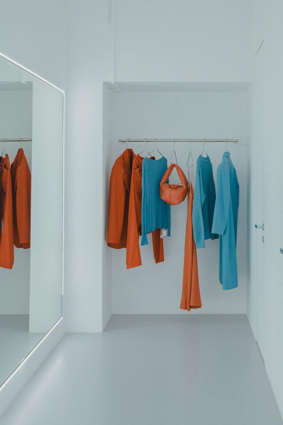 Perchero de ropa contemporáneo con prendas azules y terracota.