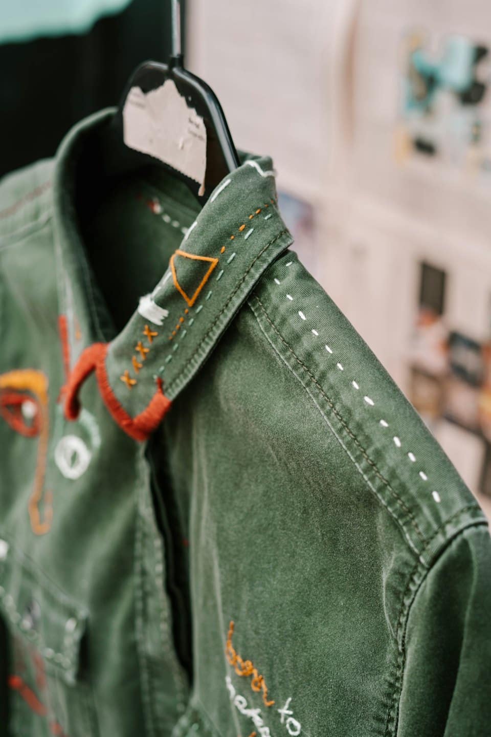 Primer plano de bordado colorido en una chaqueta verde oscuro.