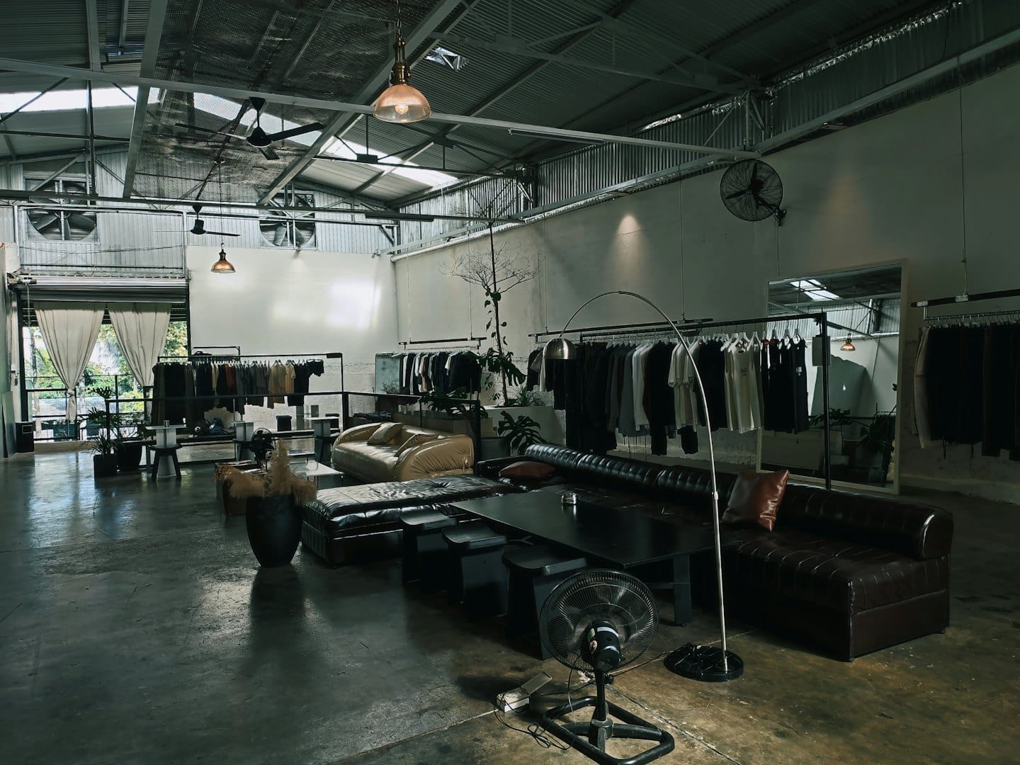 Interior de boutique moderna con percheros y dos sofás.