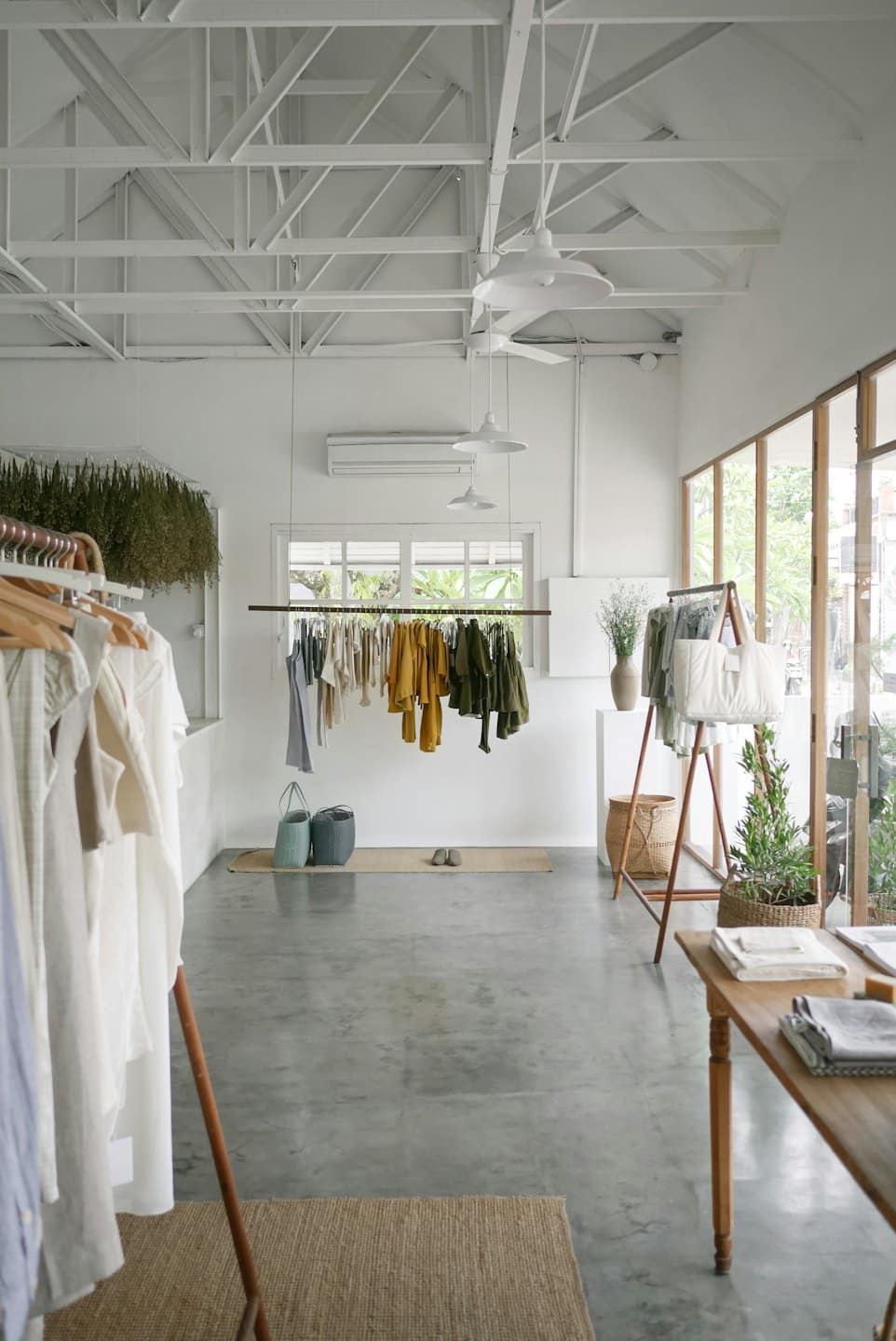 Boutique de ropa minimalista con paredes blancas y estanterías de madera.