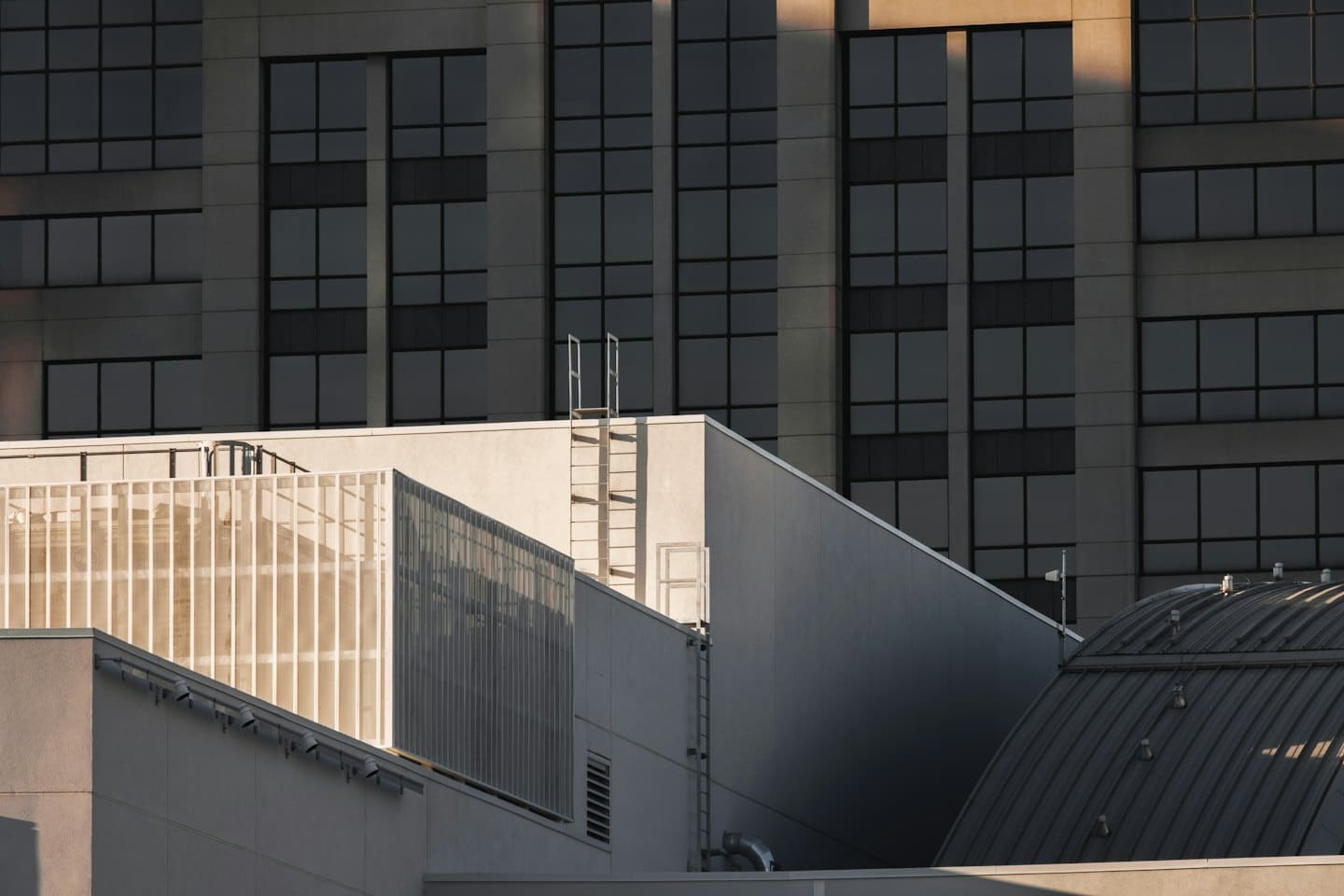 Edificios modernos de hormigón con ventanas oscuras y barandillas metálicas.